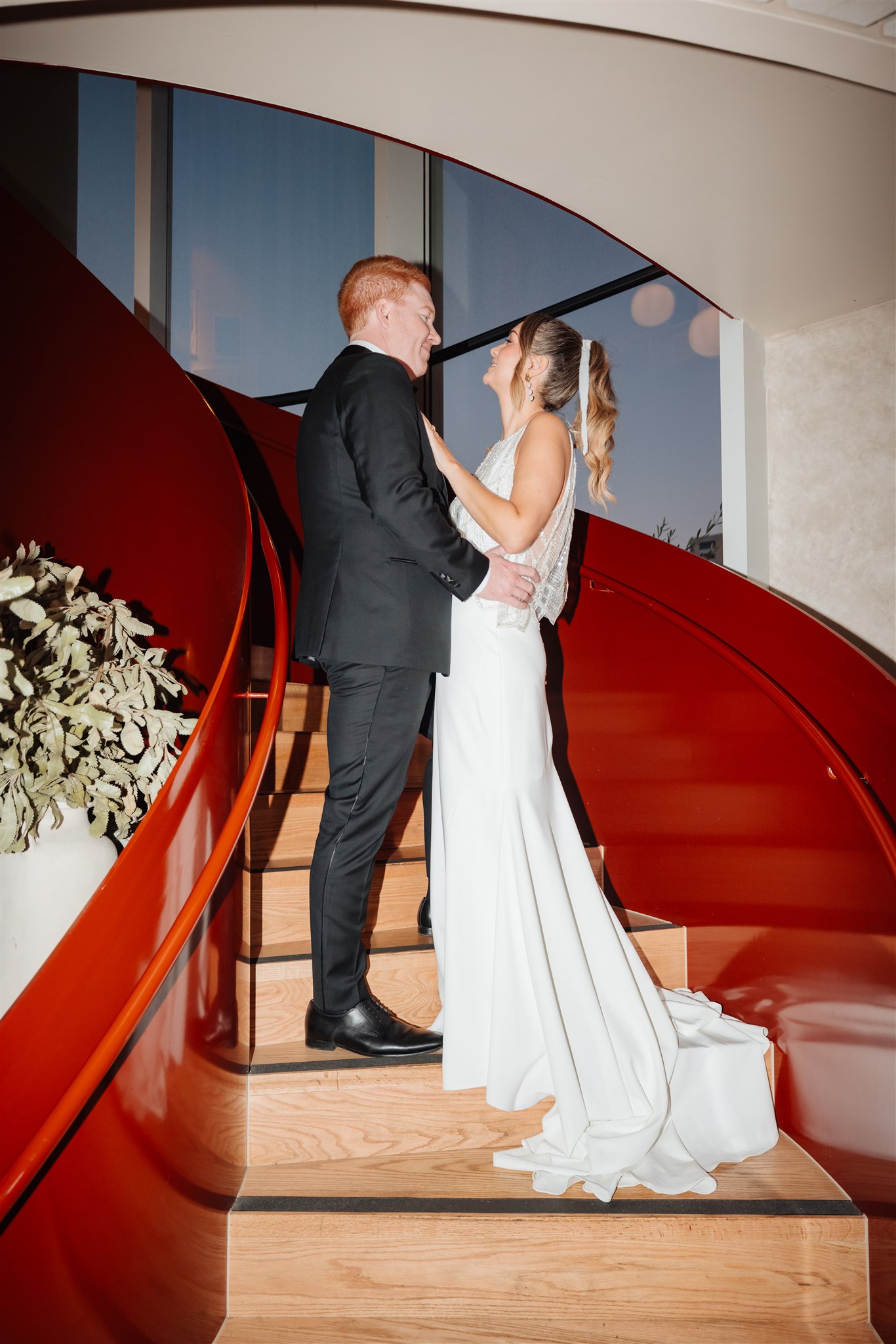 bride and groom on red spiral staircase