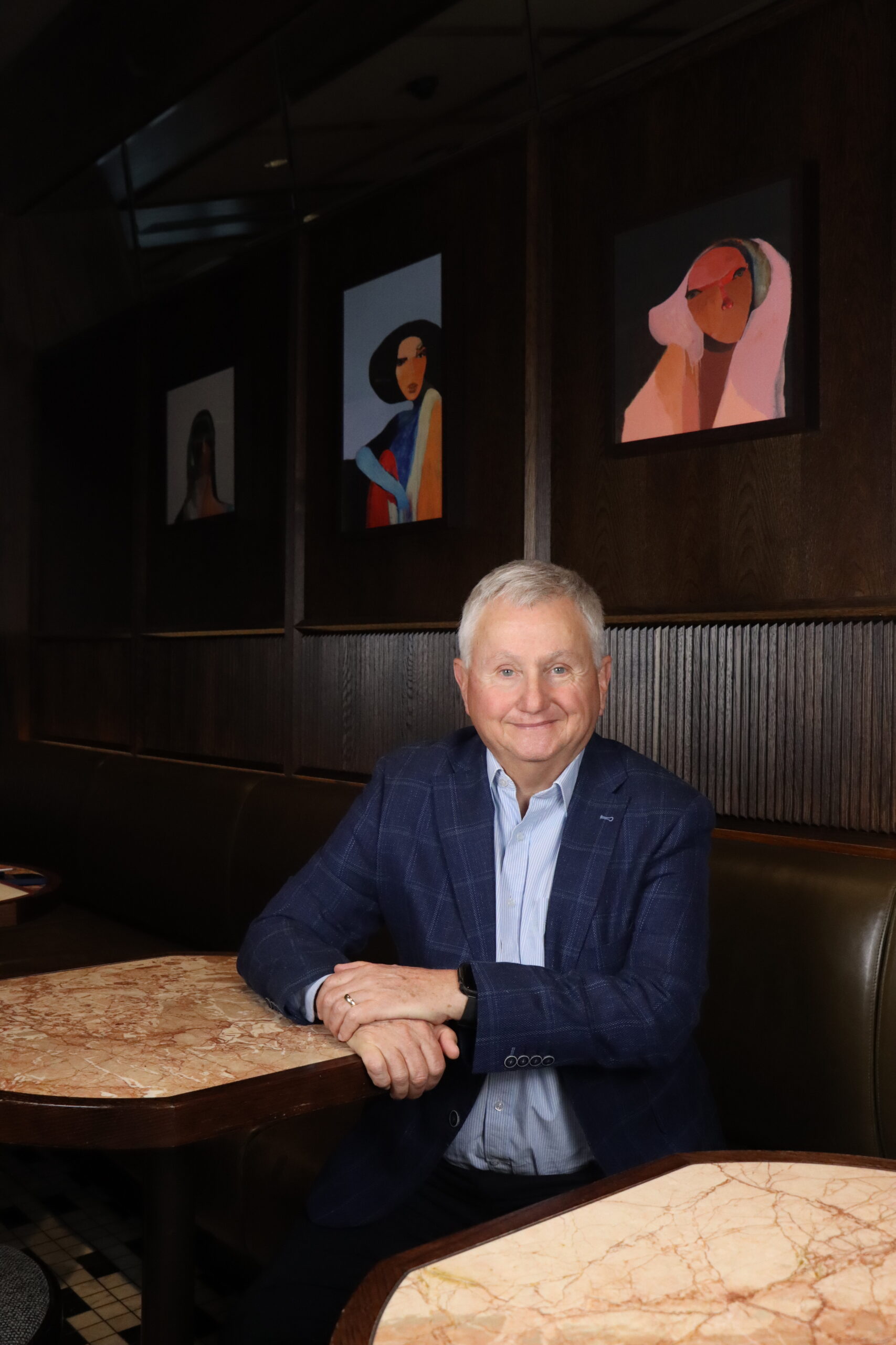 man sitting cross armed at table smiling